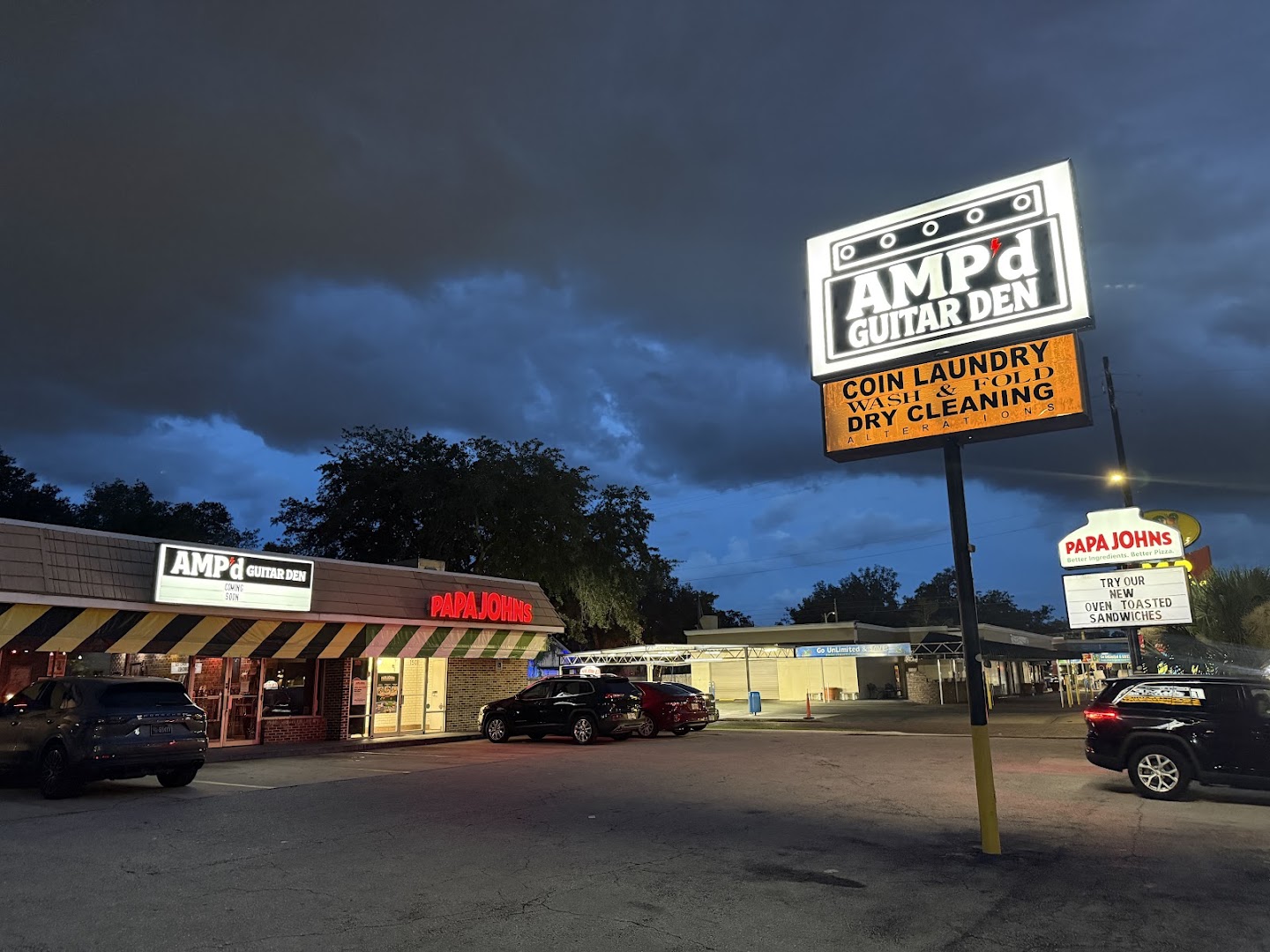 AMP'd Guitar Den: clear storefront view at night
